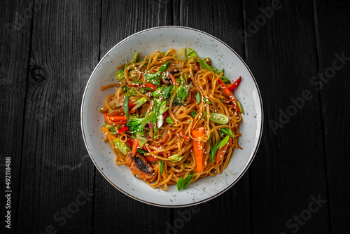 Soba Noodles with vegetables: carrots, sweet peppers, broccoli on a black background. Sushi menu. Japanese food