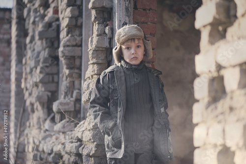 War and the child. Little scared boy in the ruins of the house. Portrait of a poor child, victim of the war.