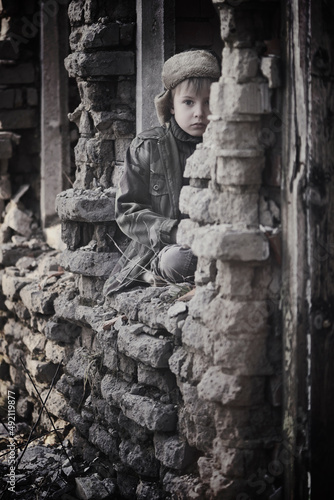 Child and war. Little, poor boy in the ruins of a bombed house.