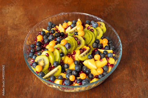 Mixed fruit salad in a glass bowl on old wooden table background