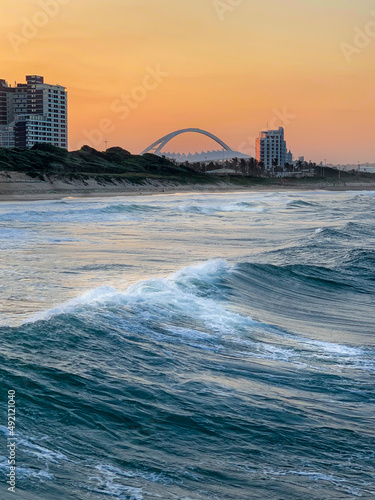 Photos View from the blue waters of the Indian Ocean to the deep orange sunset sky with the famous Moses Mabhida Sadium arch in distant background