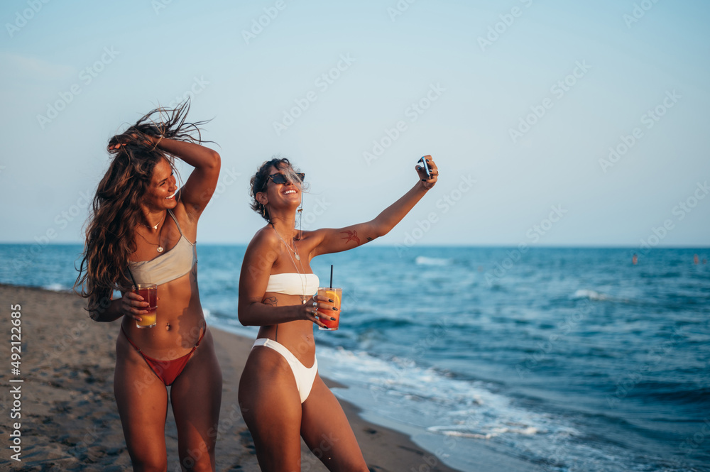 Friends enjoying vacation together and taking selfie on the beach using smartphone
