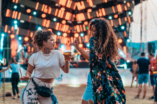 Two beautiful friends drinking beer and having fun on a music festival