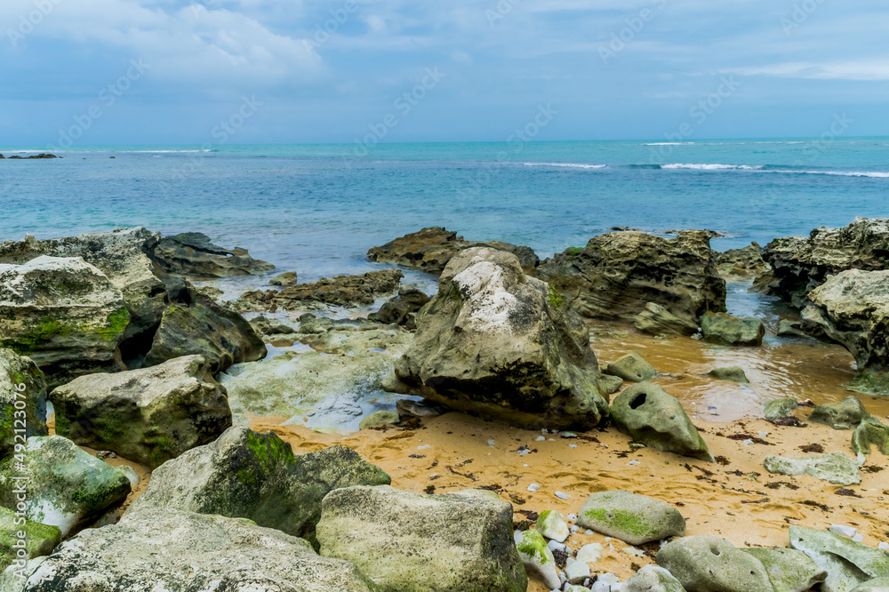 Praia com grandes pedras cheias de musgo, localizada na Praia dos Espelhos na Bahia que é um apelido devido ao efeito causado pelo reflexo do sol nas piscinas naturais quando avistadas do mar.