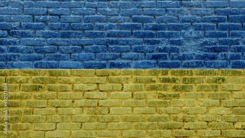 Flag of Ukraine on brick wall background on town street. Exterior stone bricks