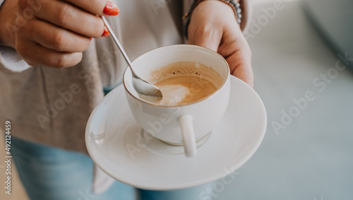 Filiżanka z kawą w dłoniach kobiety w słoneczny poranek w domu