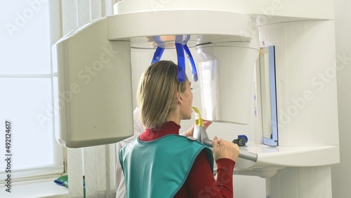 Doctor to take a image 3d scanner tomography of teeth and jaw in modern laboratory dental clinic. Female nurse shows the patient woman an x-ray machine 3d digital scanner. Computer dental diagnostics. photo