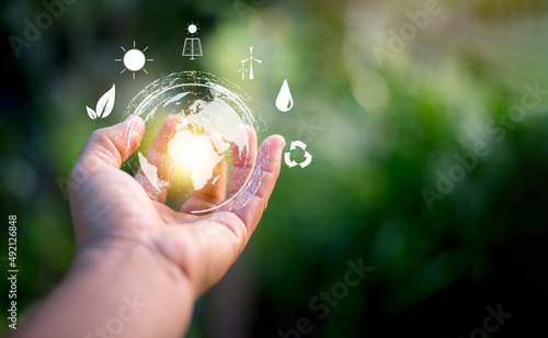 Hand holding virtual global with green background, energy saving concept, alternative and renewable energy, environmental protection and conservation , natural resources preservation.