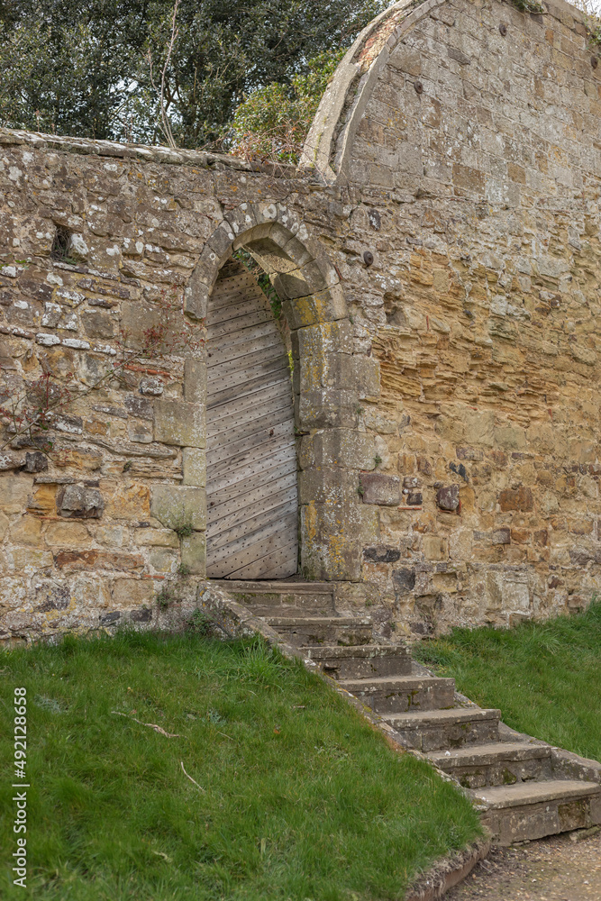 Arched doorway in a old stone wall with wooden gate