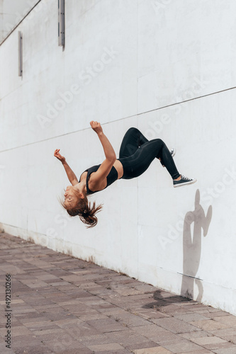 Fotografie Girl doing parkour backflip on the urban place