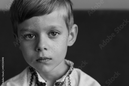 Portrait of a crying boy, loking at the camera. Child against war. Upset Ukrainian boy with, crying, protesting war conflict. Evacuation of Ukraine. Black and white crying boy.