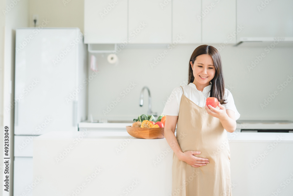 キッチンで野菜を持つ妊婦
キッチンで野菜を持つ妊婦