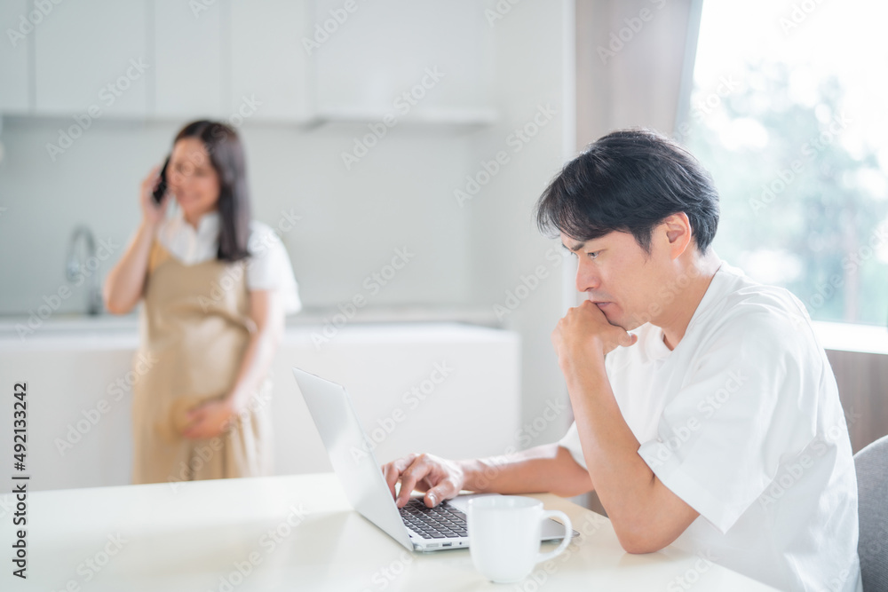 Fototapeta premium テレワークする男性と電話する妊婦(笑顔)