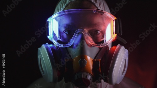 Man in protective costume suit, gas protect medical antibacterial antiviral spray paint mask. Doctor health worker in respirator. Concept health virus coronavirus epidemic. Radiation Nuclear war. photo