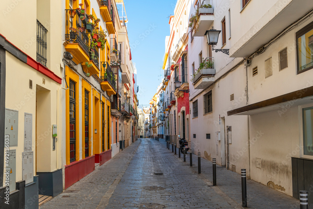 A traditional colorful residential street in the historic downtown of Seville, Spain.