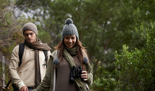 Doing bird watching. A young couple with a pair of binoculars outdoors.