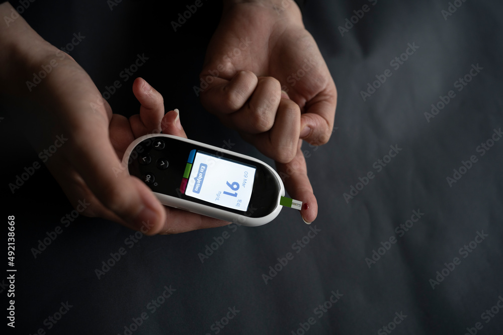 Caucasian young woman using digital glucometer at home. Caucasian young woman using digital glucometer at home.