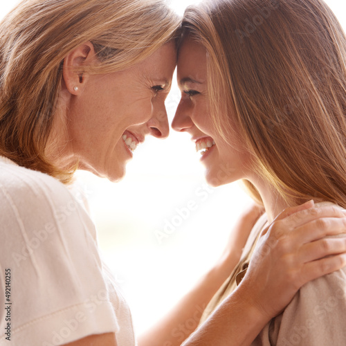 You really do light up my life. A mother and daughter standing face to face and showing each other affection.
