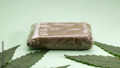 large portion hashish tablet with marijuana leaf, green background