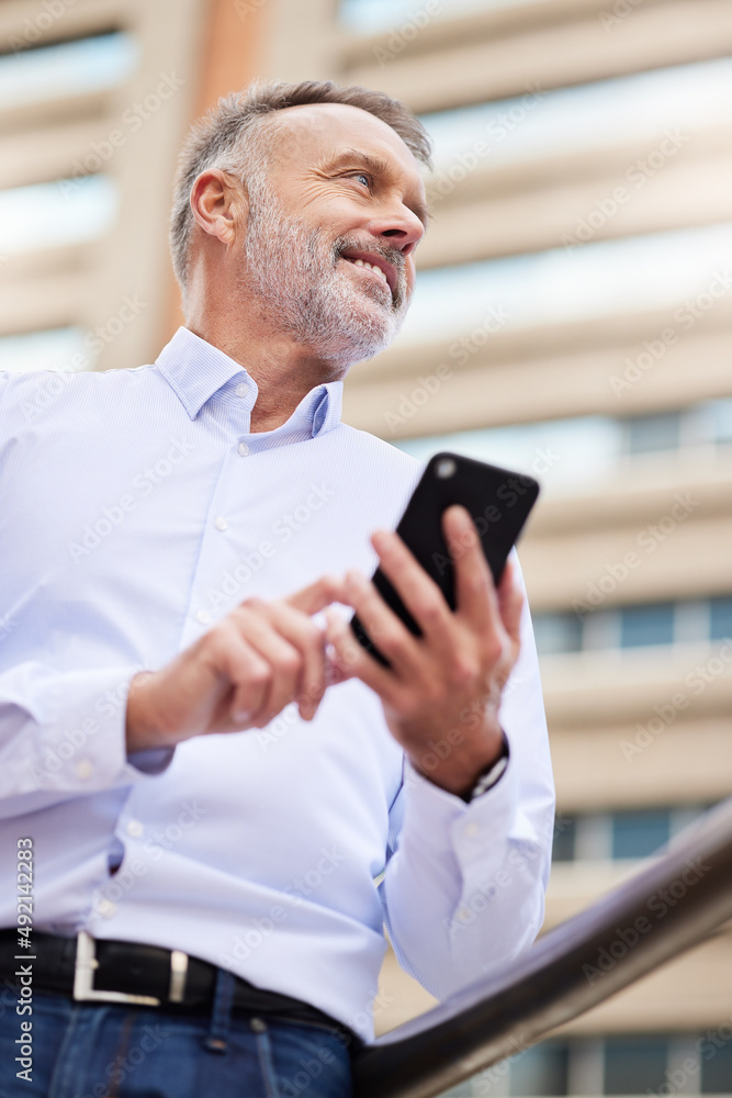 My client is on their way. Shot of a handsome mature businessman standing alone on the balcony outside and using his cellphone. My client is on their way. Shot of a handsome mature businessman standing alone on the balcony outside and using his cellphone.