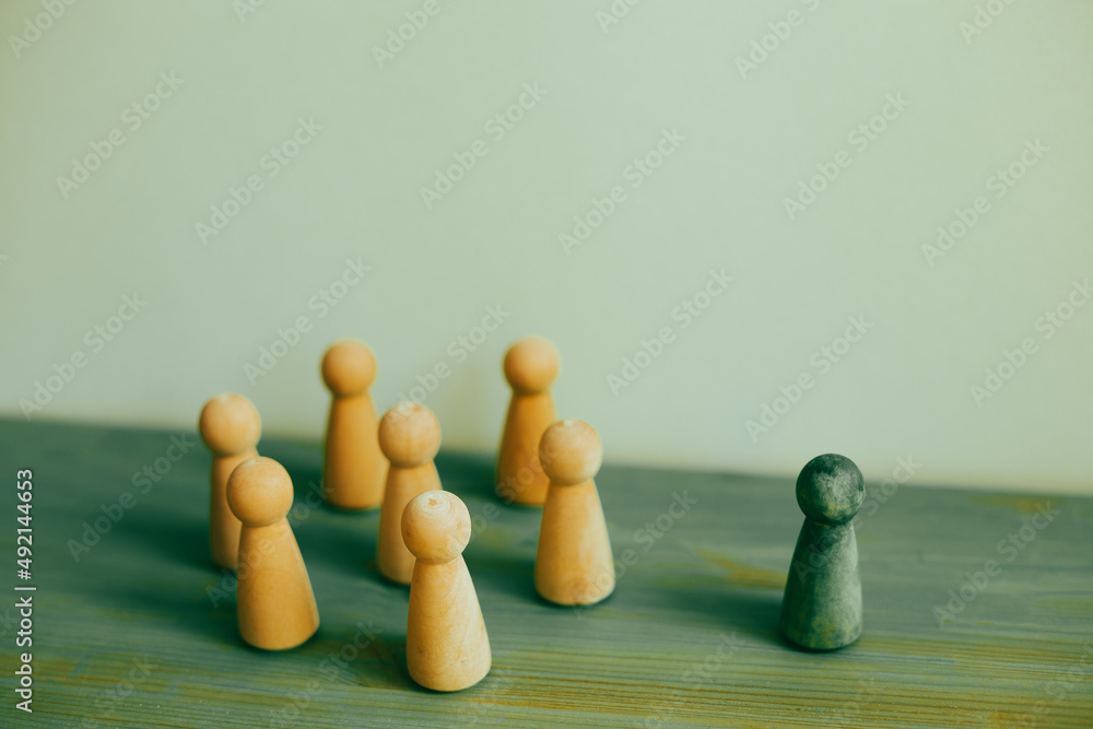 Majority vs minority concept. Wooden human figure on desk. green background