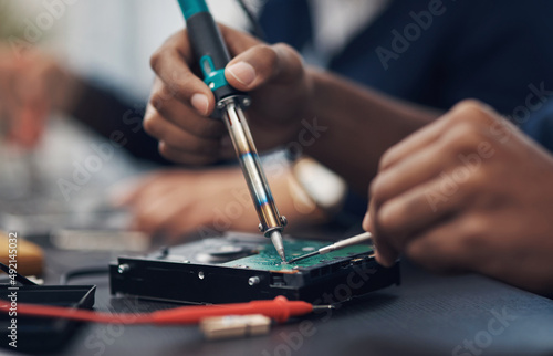 The master at making any computer hardware work. Shot of a technician using a soldering iron .to repair computer hardware.