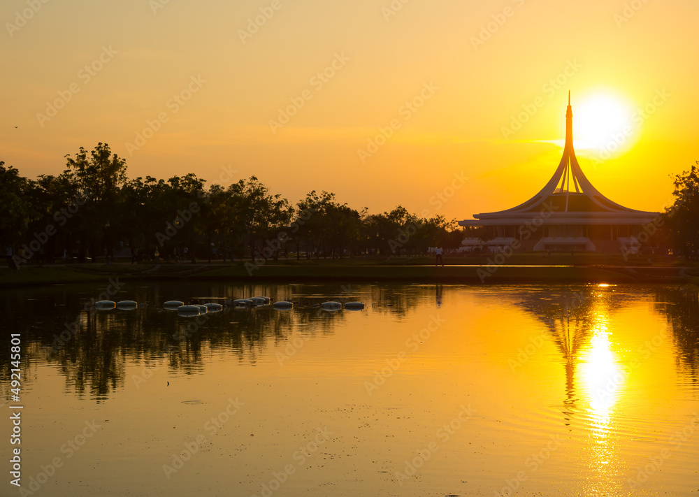 Perfect reflections of iconic building on water pond at Suan Luang Rama IX Park, landmark of Thailand with beautiful sunset sky.