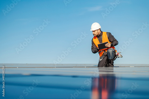A worker using tablet to test solar panels on the rooftop.