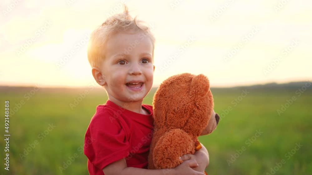 portrait of a baby boy with a toy teddy bear in his hands on nature in ...