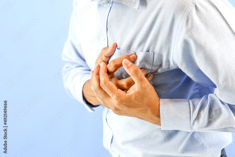 Hand squeezing the left chest pain on blue background concept of heart