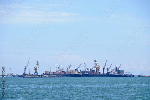 Many logistic transportation ships with cranes to move cargos around floating in the ocean on sunny day © eyeofpaul