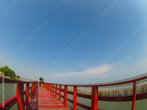 Red long timber boardwalk is tourist attraction alongside a waterfront near coastal line in Samut Prakan  Thailand  the image was taken by wide angle lens.