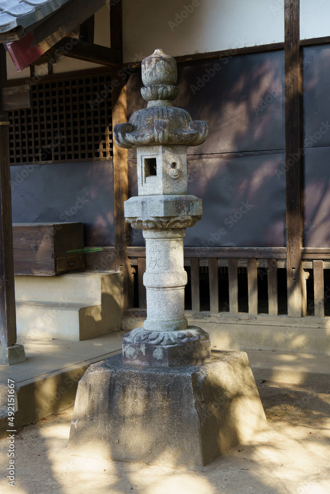 Naklejka premium 神社の境内に灯をともす石の灯篭