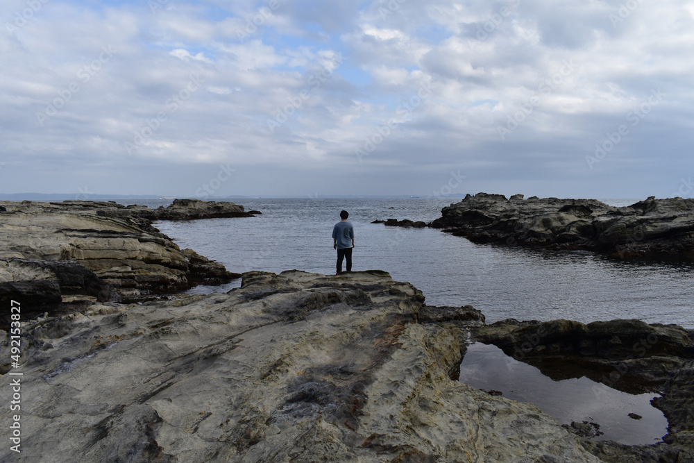 海の岩に立つ男性