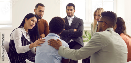 Supportive multiracial people comfort cheer depressed female group member suffer from psychological problem. Caring diverse friends support woman at therapy or session. Counseling help concept.
