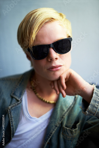 Hes got attitude. Attractive young guy wearing hipster shades with his hand on his chin.