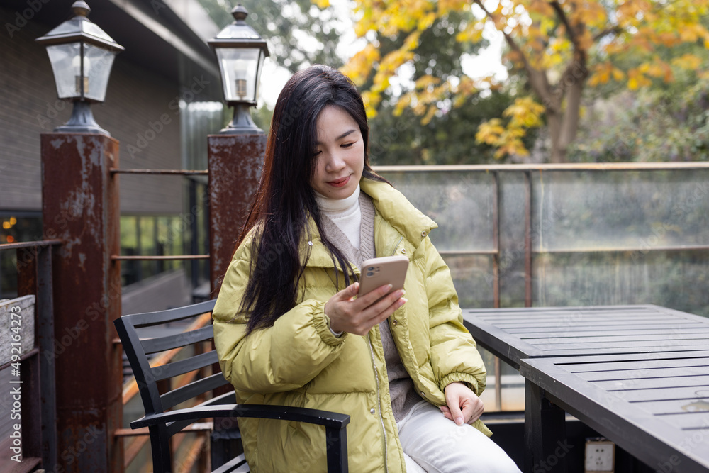Stylish Young Asian beautiful woman using smart phone for in outdoor cafe at spring or autumn season. Blogger streaming broadcast for social media and communicating with followers Stylish Young Asian beautiful woman using smart phone for in outdoor cafe at spring or autumn season. Blogger streaming broadcast for social media and communicating with followers