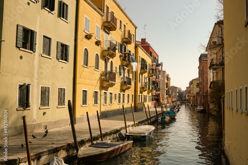 Small Venetian side street with colorful houses and a small canal with boats.