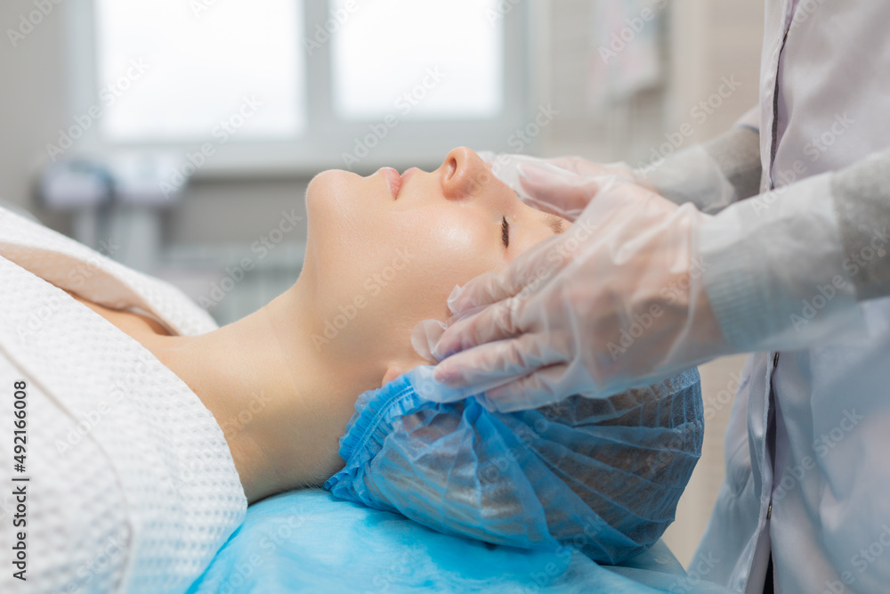 Side view of a girl relaxing on a couch during a facial massage in a beauty salon. Moisturizing and rejuvenation of the facial skin