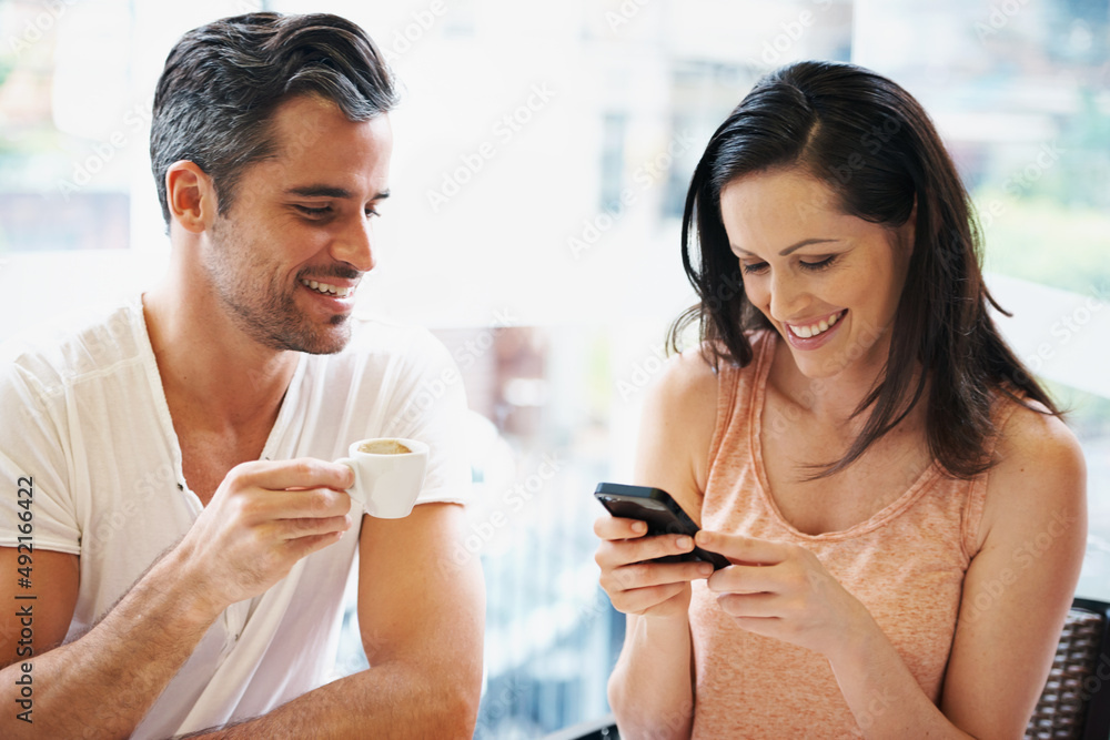 Im so happy I want everyone to know. Shot of a young woman using her mobile phone during a coffee date. Im so happy I want everyone to know. Shot of a young woman using her mobile phone during a coffee date.