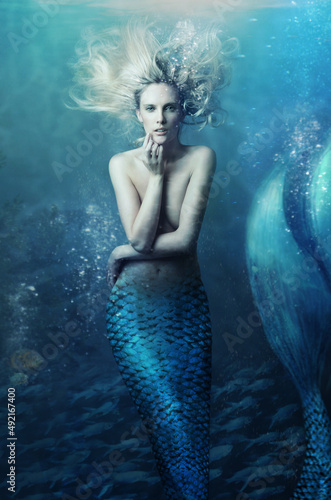 Fototapeta Shot of a mermaid swimming in solitude in the deep blue sea - ALL design on this
