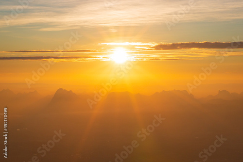 Mountains in clouds at sunrise in summer. Aerial view of mountain peak in fog. Beautiful landscape with high rocks, forest, sky. Top view from drone of mountain valley in low clouds. Foggy hills  © banjongseal324