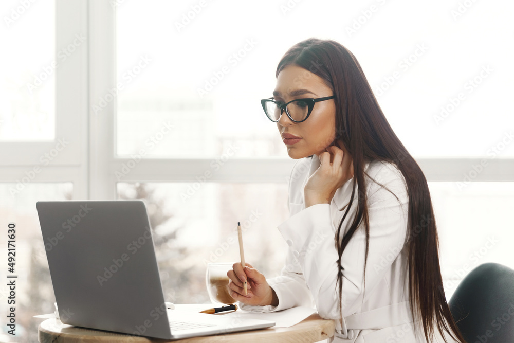Beautiful woman sit indoors in office using laptop computer Beautiful woman sit indoors in office using laptop computer