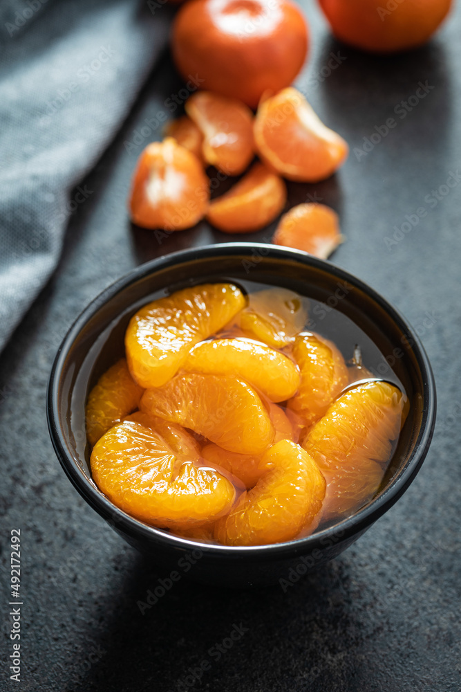 Canned tangerine. Pickled mandarin fruit in bowl on black table. Canned tangerine. Pickled mandarin fruit in bowl on black table.