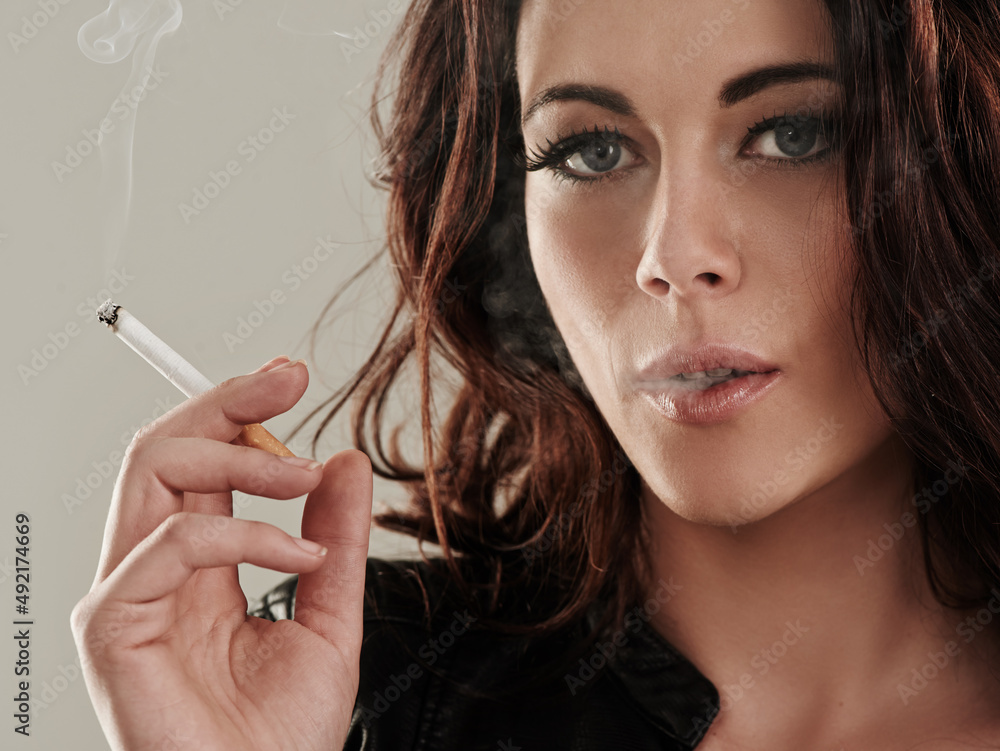 Obraz premium Shes a bad girl by nature. Portrait of an attractive young woman smoking a cigarette.