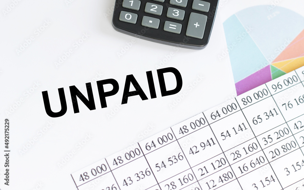 Unpaid. Text in a notebook and on a white background with a calculator Unpaid. Text in a notebook and on a white background with a calculator