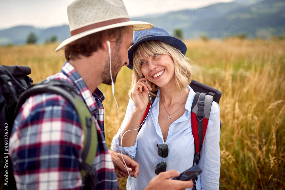 .Romantic man and woman sharing headphones at nature and listening music