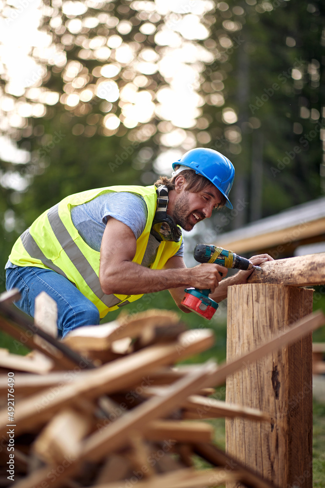 A young male builder working at a construction site in the forest. Construction, building, workers A young male builder working at a construction site in the forest. Construction, building, workers
