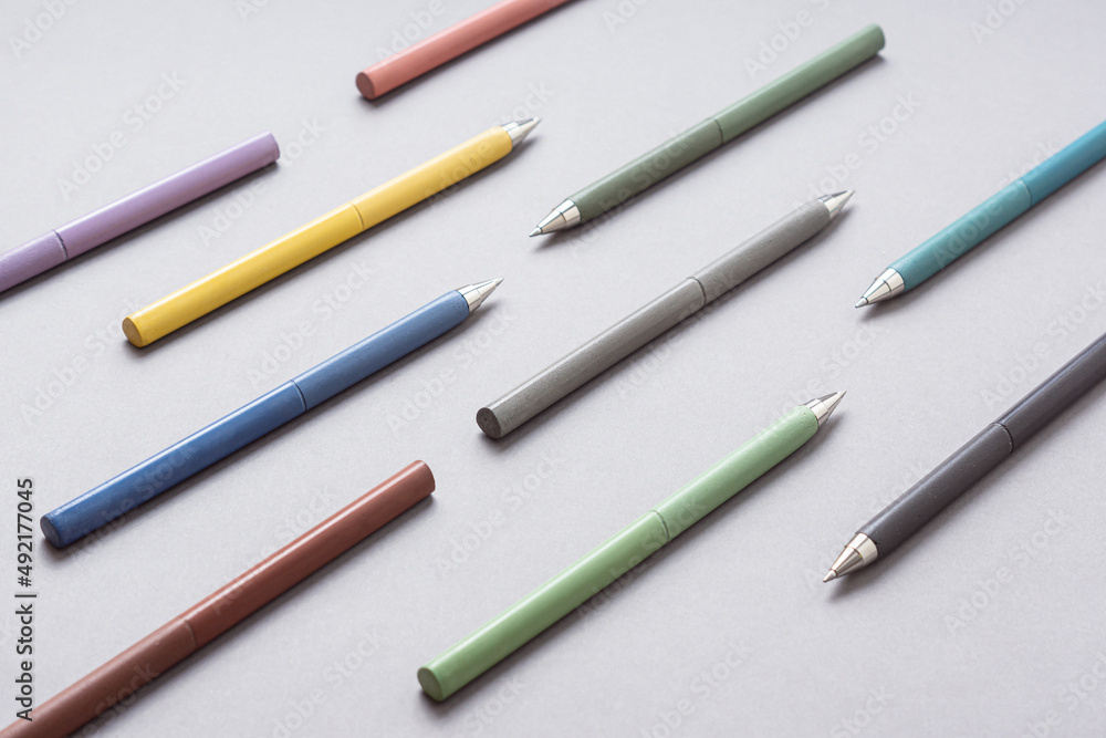 Set of multi-colored pens on gray background. Pattern. Ballpoint pens for pupils, students Set of multi-colored pens on gray background. Pattern. Ballpoint pens for pupils, students