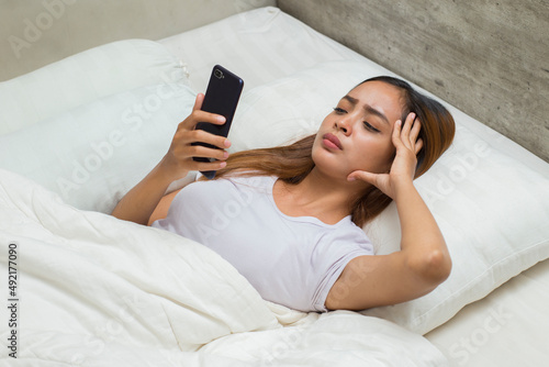 unhappy asian beautiful girl feeling sad using smartphone on bed 